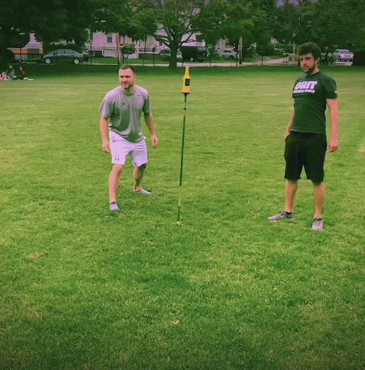 video clip of frisbee hitting pole and a guy catching the frisbee, turning it upside down and catching a bottle in it.