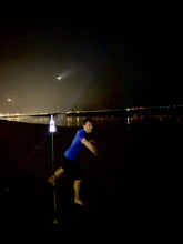 Load image into Gallery viewer, a man playing bottle bash at night with the bottle glowing
