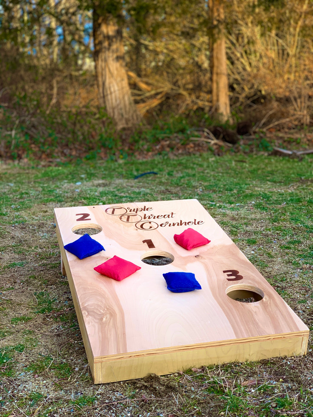 triple threat cornhole yard game with red and blue bags